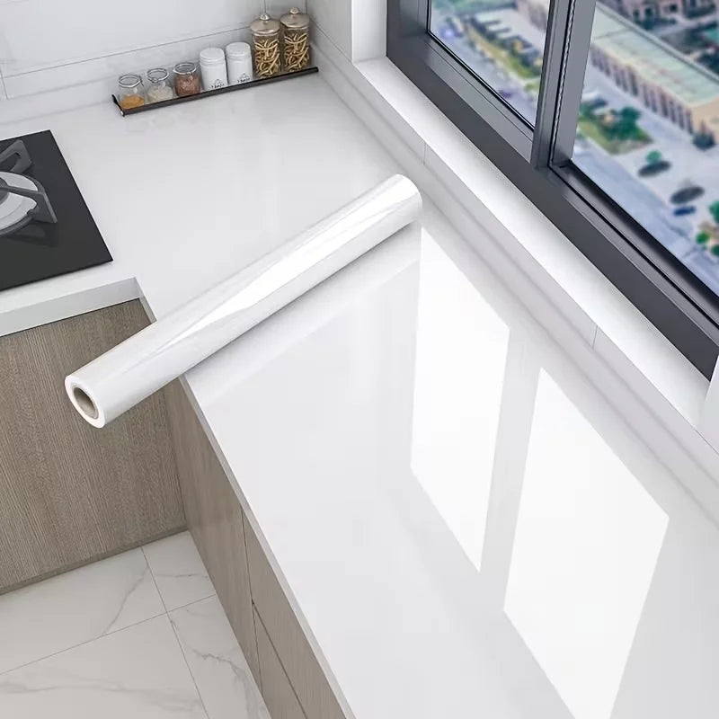 A roll of pearlescent PVC self-adhesive wall stickers displayed on a white countertop near a window.