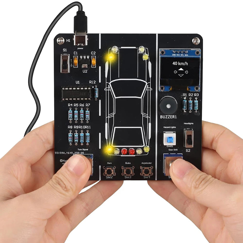 A hand holds a black electronic kit for car driving simulation with various components and wires.