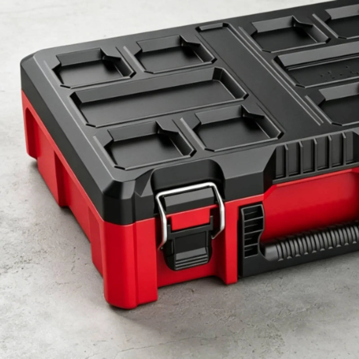 A red and black heavy duty modular tool storage case with compartmentalized inserts is shown on a gray surface.