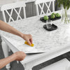 A hand is applying pearlescent PVC self-adhesive wall stickers for home decor onto a white marble tabletop.