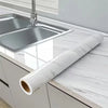 Roll of pearlescent PVC self-adhesive wall stickers displayed on a kitchen countertop next to a stainless steel sink.