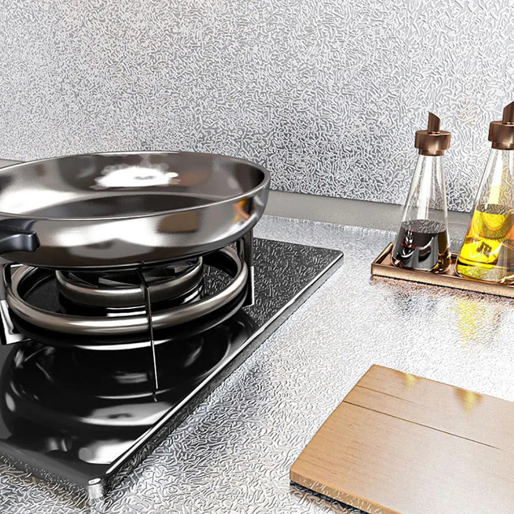 A black induction cooktop with a pan on it, next to glass bottles of yellow liquid and a wooden board.