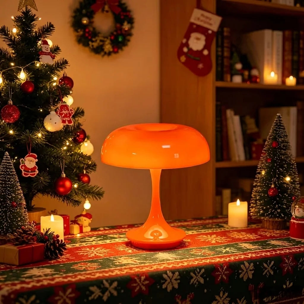 Una lámpara de escritorio naranja con pantalla abovedada suave sobre una mesa festiva de Navidad.