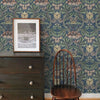 Cómoda de madera oscura con un cuadro y una silla de madera contra papel tapiz floral de damasco vintage.