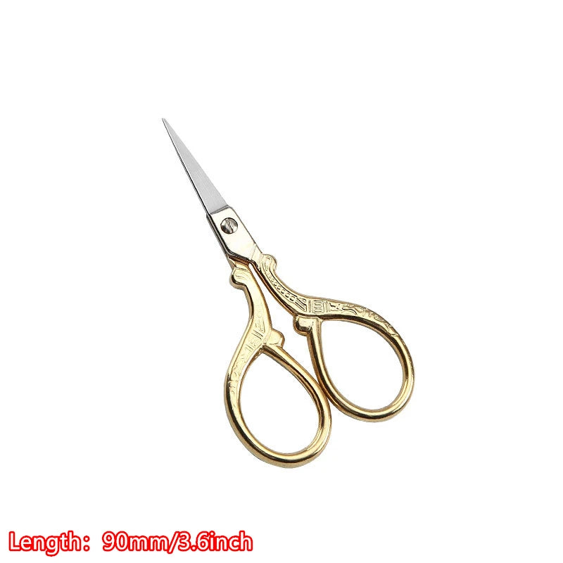A pair of vintage floral embroidery tailor scissors with gold-toned handles and silver blades.