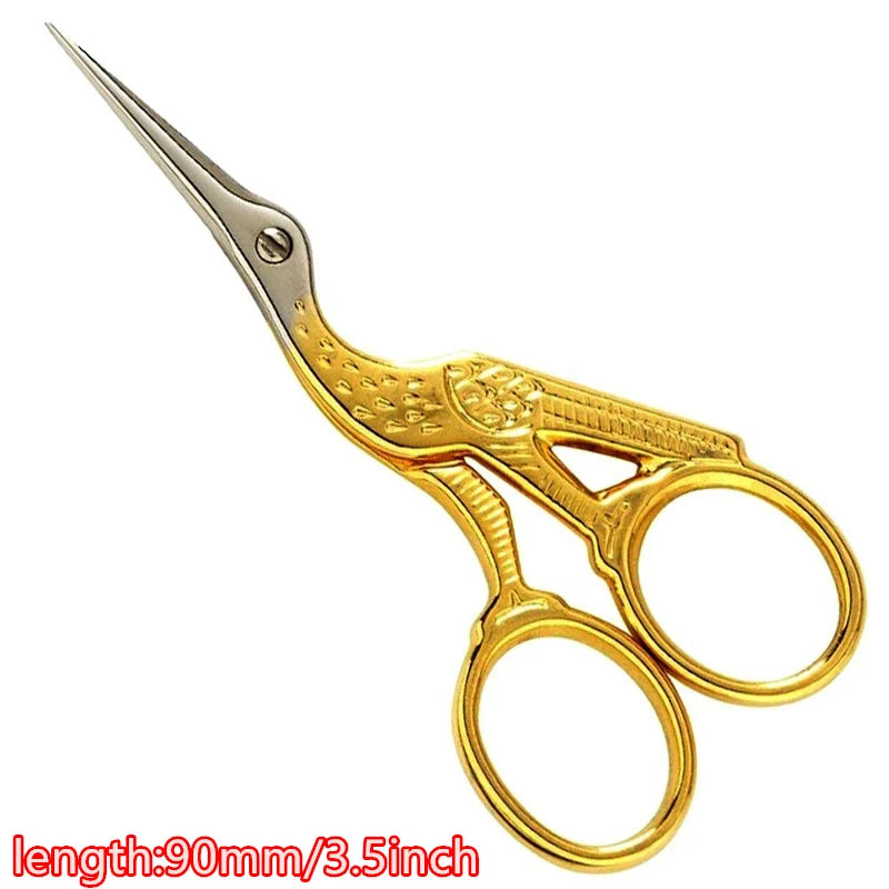 Gold-colored tailor scissors with a floral pattern and pointed tips.
