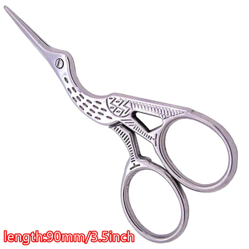 Silver vintage tailor scissors with a floral pattern and a long, pointed tip.