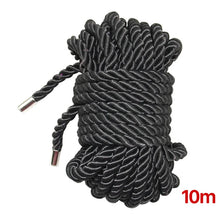 A thick black soft silk bondage rope coiled and bundled together.