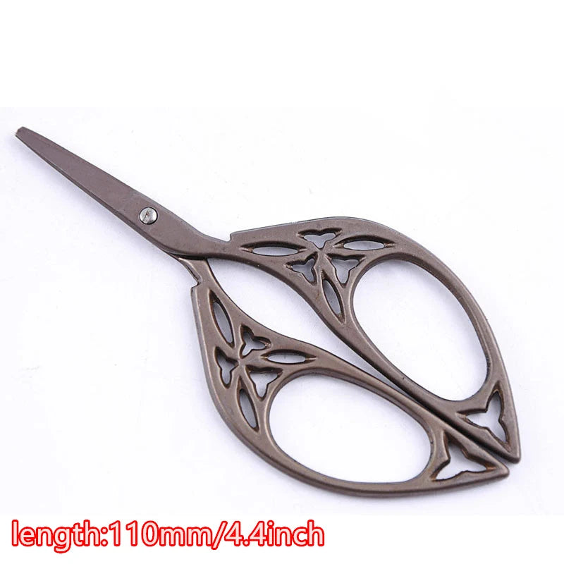 A pair of vintage floral embroidery tailor scissors with a dark metal finish.