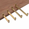 Four modern golden brass cabinet handles displayed on a wooden surface.