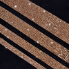 Nahaufnahme von goldenen Glitzer-Strassstreifen, diagonal auf dunklem Hintergrund.