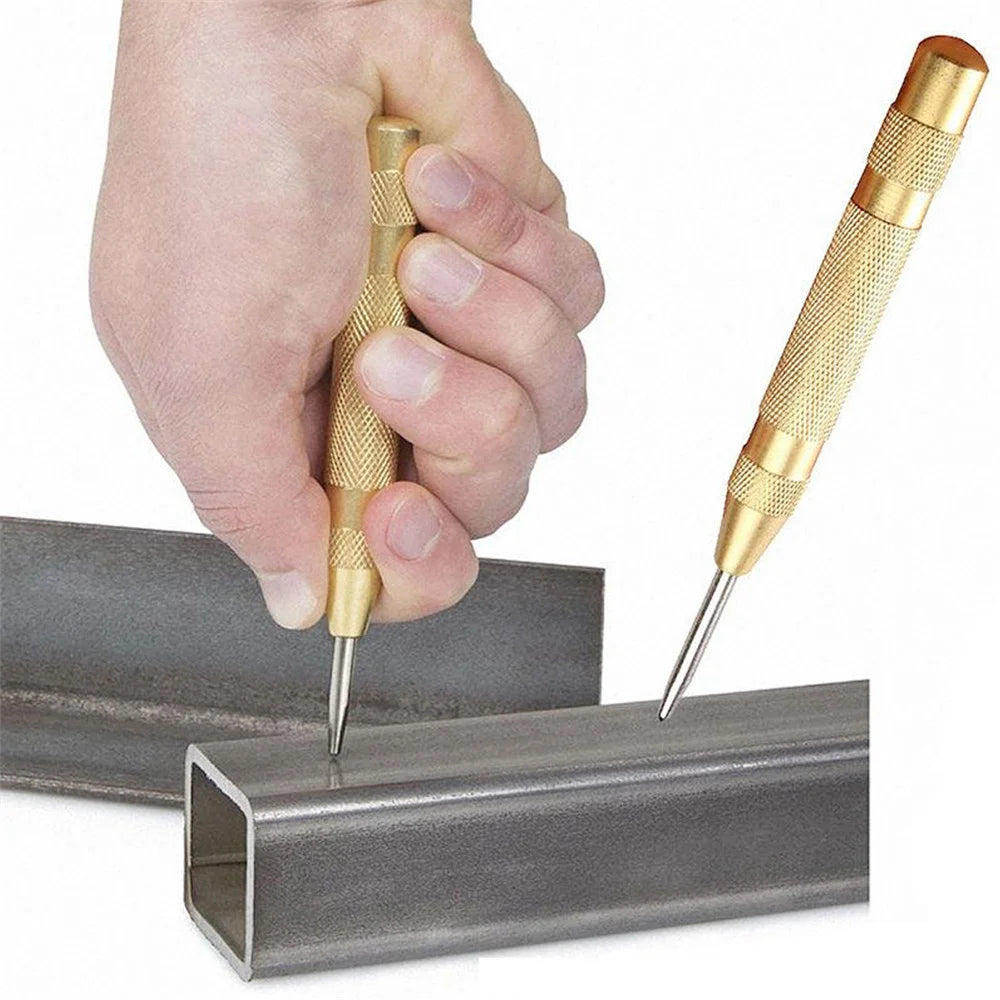 A hand is using a spring-loaded center pin punch to pierce a metal bar.