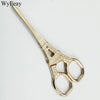 A pair of vintage gold-toned tailor scissors with floral embroidery detail.