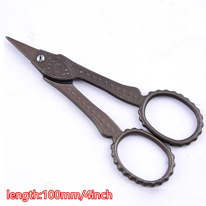 A pair of vintage floral embroidery tailor scissors with a dark brown handle and silver pivot.