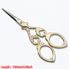 A pair of vintage gold-colored tailor scissors with floral embroidery detailing.