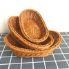 A stack of natural rattan woven serving baskets in warm brown tones on a gray checkered surface.