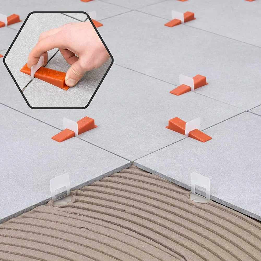 A hand is using a precision tile leveling spacer to mark a line on a gray tiled floor.