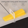 Yellow leveling spacer with a secure buckle shown on a wooden surface.