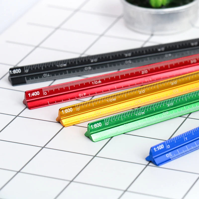 A collection of multicolor aluminum triangular rulers with various scales laid out on a white grid background.