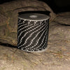 A roll of black and white reflective paracord rope resting on a gray rock.