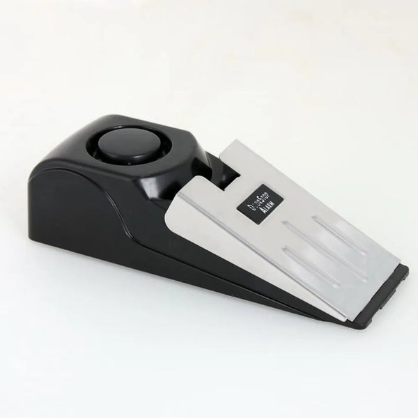 A black door stop security alarm wedge with a white plastic body and a round sensor top.