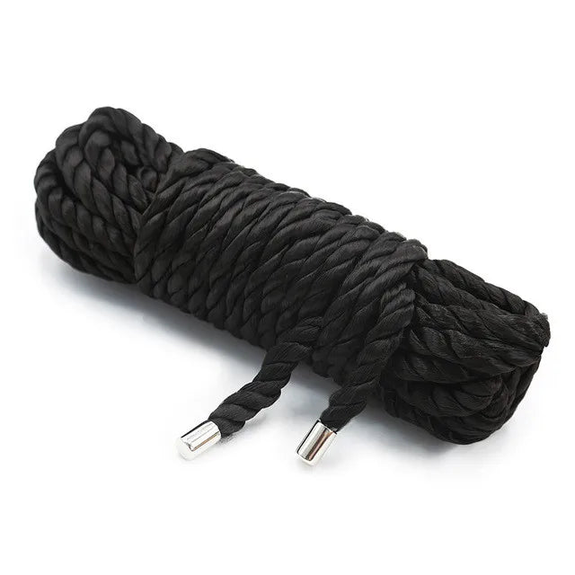 A coil of black silky bondage rope used for restraint and roleplay.