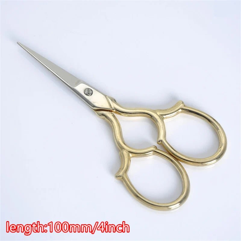 A pair of vintage floral embroidery tailor scissors with a gold-toned handle and silver blades.