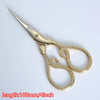 A pair of vintage gold-colored tailor scissors with a pointed tip and decorative floral patterns.