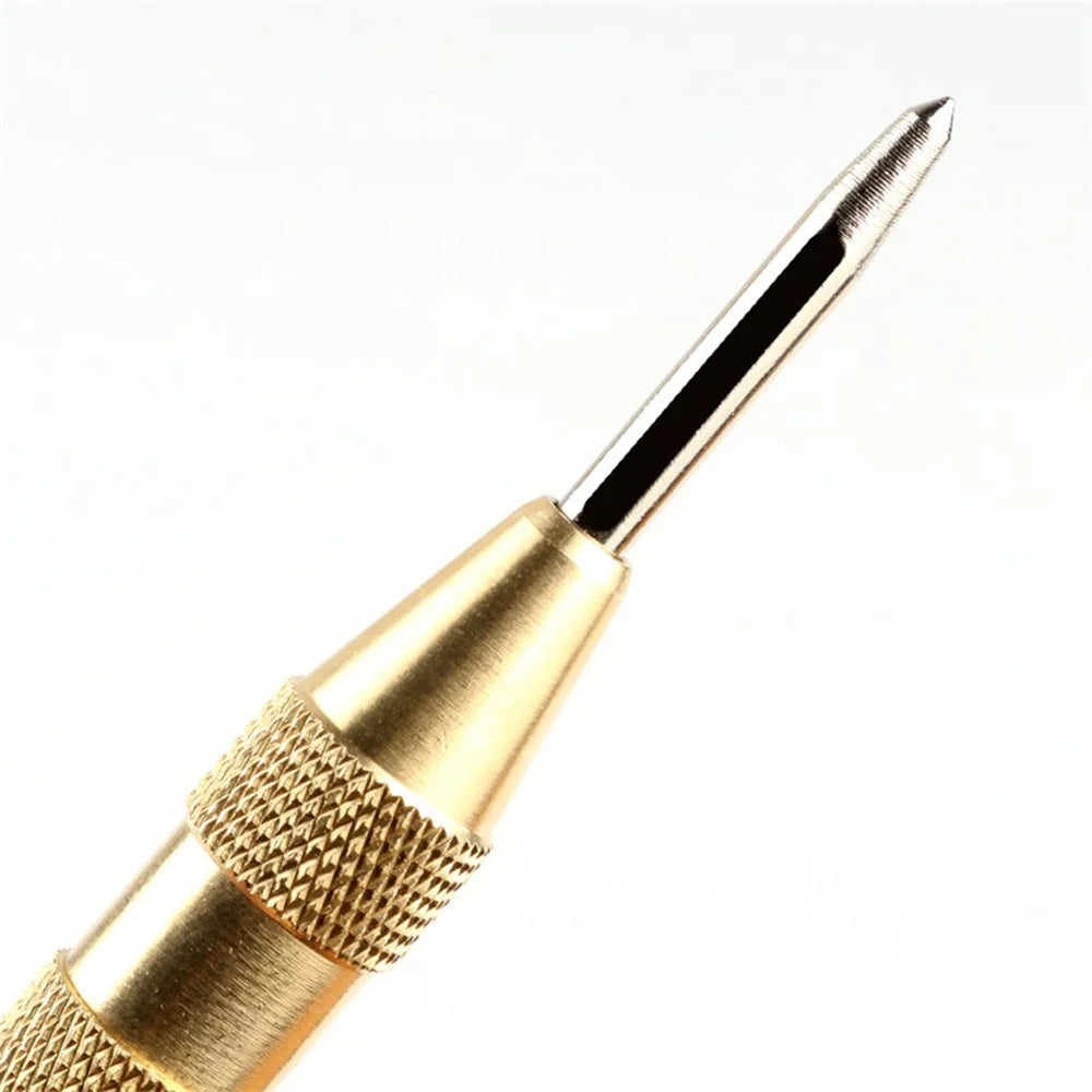 A close-up view of a gold-colored spring-loaded center pin punch with a textured grip and sharp point.
