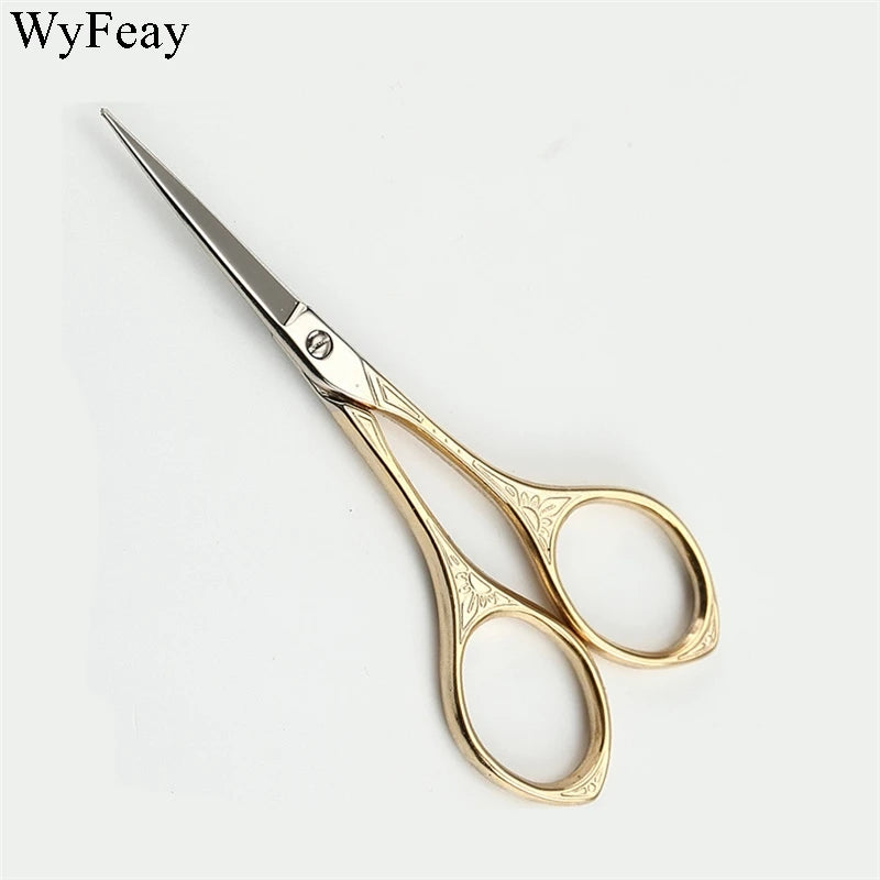 A pair of vintage floral embroidery tailor scissors with gold-toned handles and silver blades.