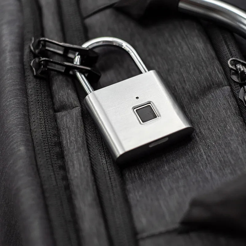 A silver fingerprint keyless door lock is shown attached to a black fabric or leather item.
