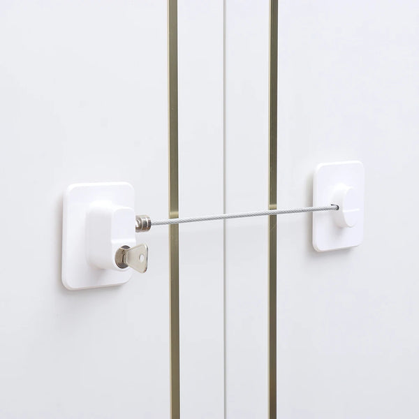A white universal safety lock is installed on a white cabinet door, featuring a silver latch and a long metal rod.