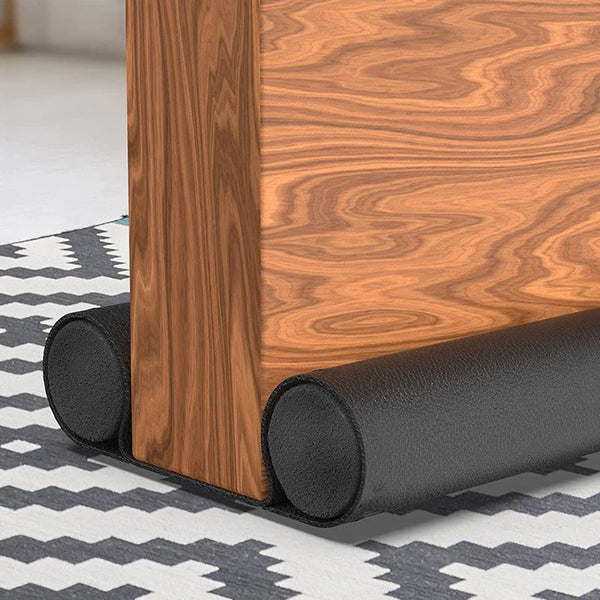 A close-up of a wooden door frame with a black flexible sealing strip installed at the bottom edge.