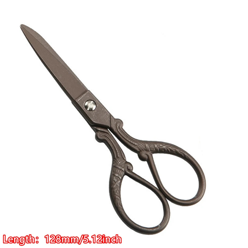 A pair of vintage floral embroidery tailor scissors with a dark metal finish.