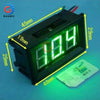 A black digital voltmeter gauge with a green display and a small rectangular component placed next to it.