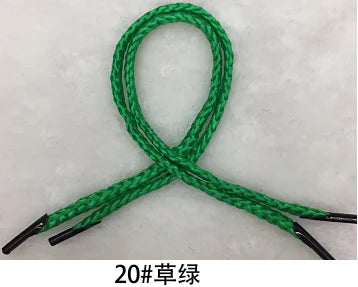 A green gift wrapping rope is shown tied in a loop and crossed, with black tips visible.