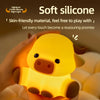 A hand is holding a soft silicone Highland cattle night light lamp with a yellow body and brown accents.