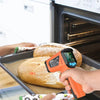 Une main utilise un thermomètre infrarouge numérique pour mesurer la température interne d'une miche de pain au four.