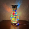 Lámpara de mesa de cristal con forma de jarrón, con patrones de mosaico coloridos e iluminada desde abajo.