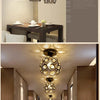 A modern crystal LED chandelier lamp hanging in a room, with a long hallway visible in the background.