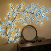 A branch-like LED cherry blossom tree light decoration mounted on a wall above a mirror.