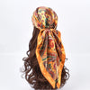 Foulard hijab en satin soie orange vif avec motifs paisley et floraux, noué autour d'une chevelure brun foncé.