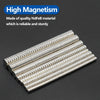 A collection of silver neodymium fridge magnets arranged in a diagonal line on a dark surface.