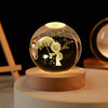 A glass crystal ball night light illuminates a silhouette of a figure and stars on a wooden base.