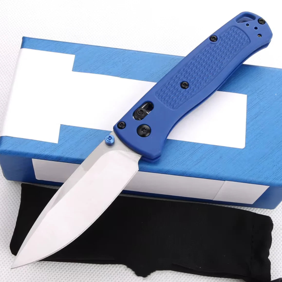 Un couteau à pliage bleu avec étui noir posé sur une boîte blanche.
