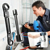 A man is using a professional double-ended pipe wrench set on a pipe in a workshop setting.