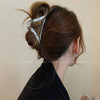 A close-up of a woman's hair styled in an updo with elegant gold S-shaped metal hair clips.