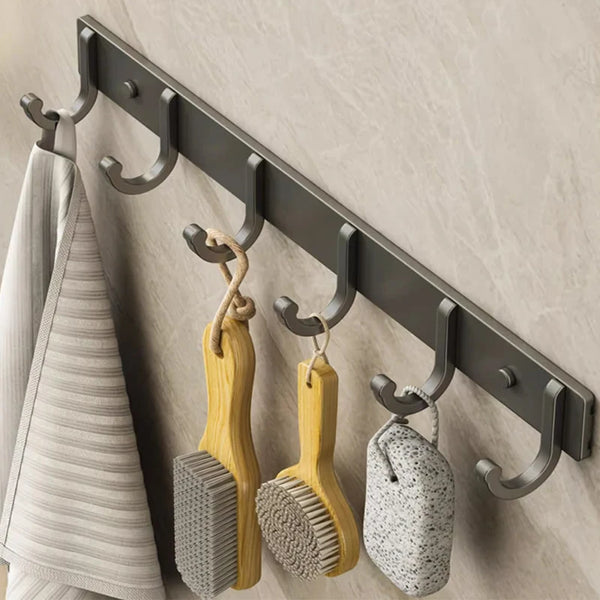 Un ensemble de crochets en aluminium spatial accrochés au mur, avec des porte-crochets en bois et silicone texturé.