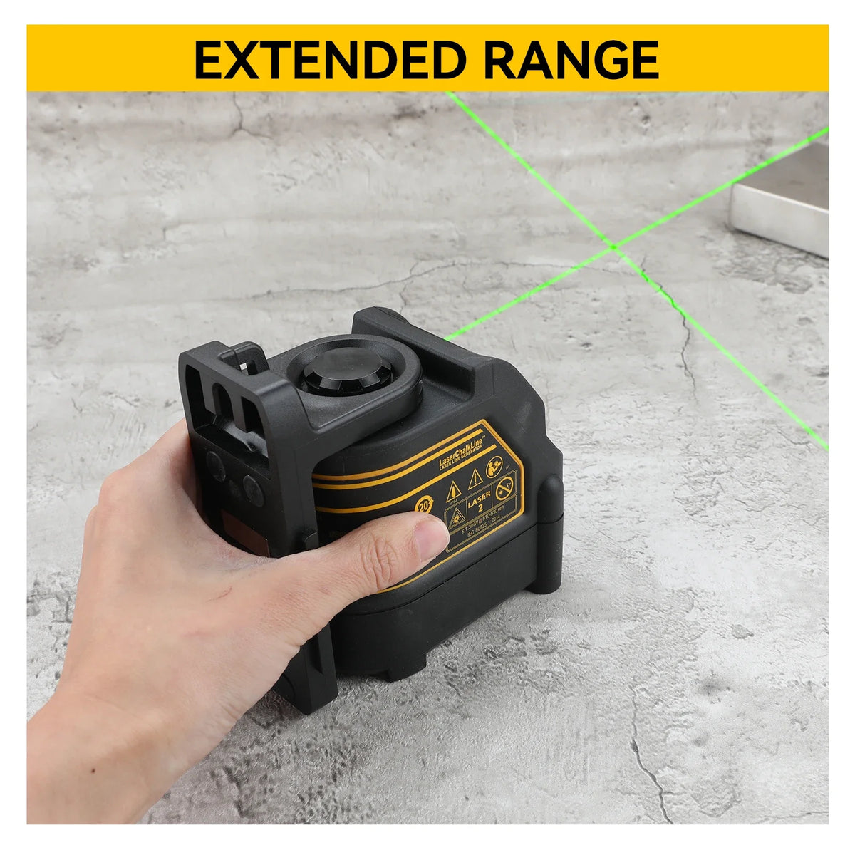 A hand holds a black professional laser level tool with an extended range feature against a gray background.
