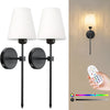 A pair of modern black wall lamps with white shades mounted on a wall, shown alongside a remote control and color spectrum.
